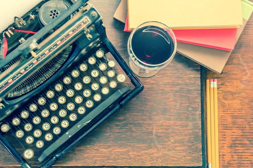 Typewriter, blank pages, and coffee in a wine glass. Let's get started.